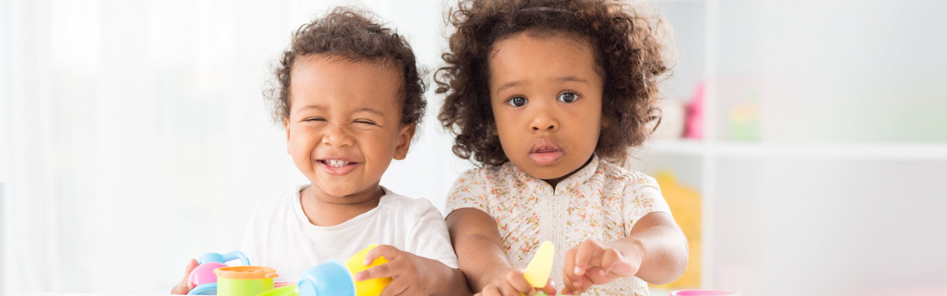 two toddler playing and smiling